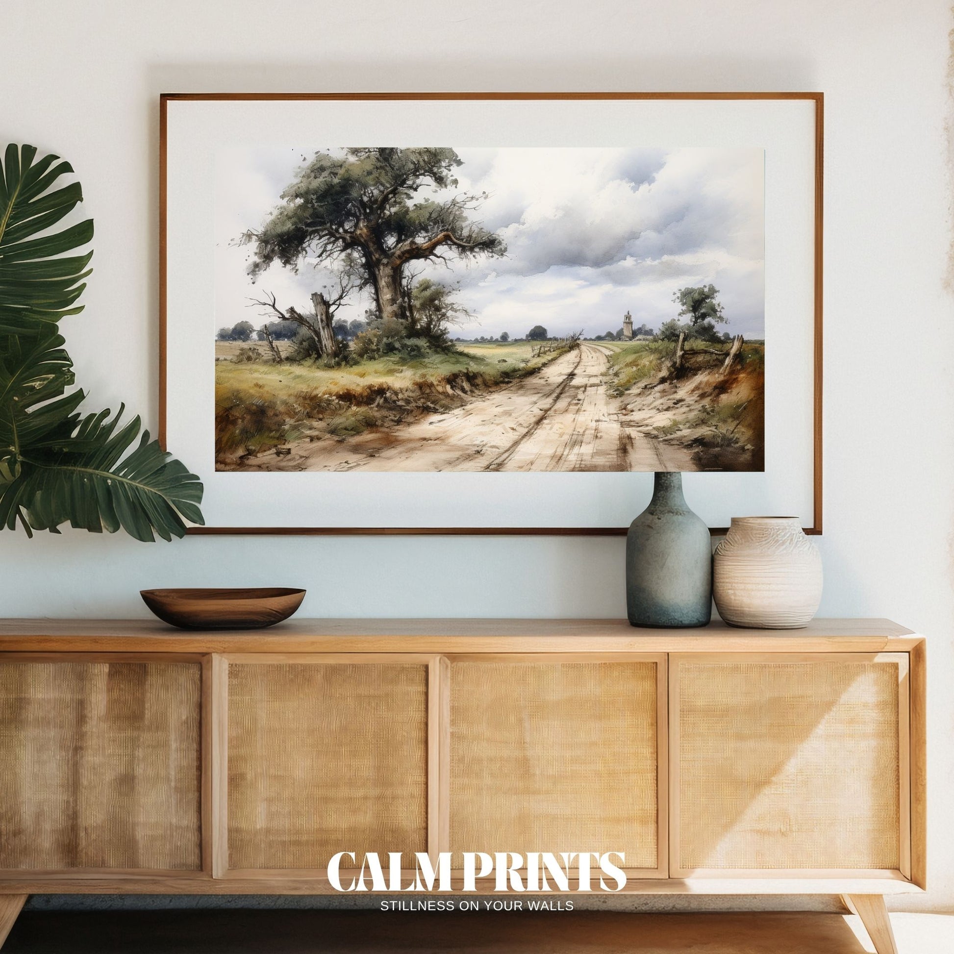 Landscape view of a winding road leading to a tree and distant tower
